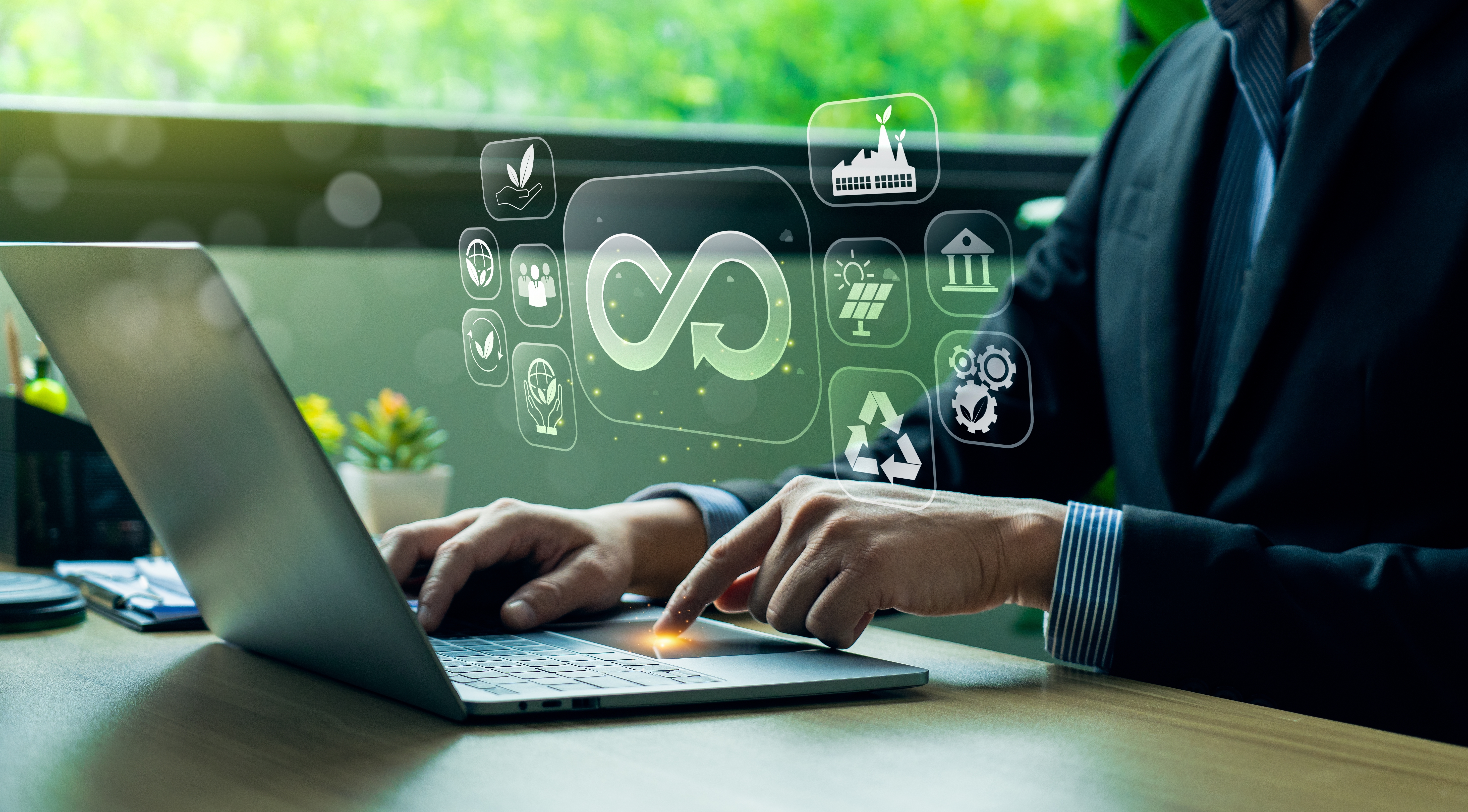 Un homme appuie sur le touchpad d'un clavier, des visuels relatifs à l'économie circulaire apparaissent au dessus de ses mains.